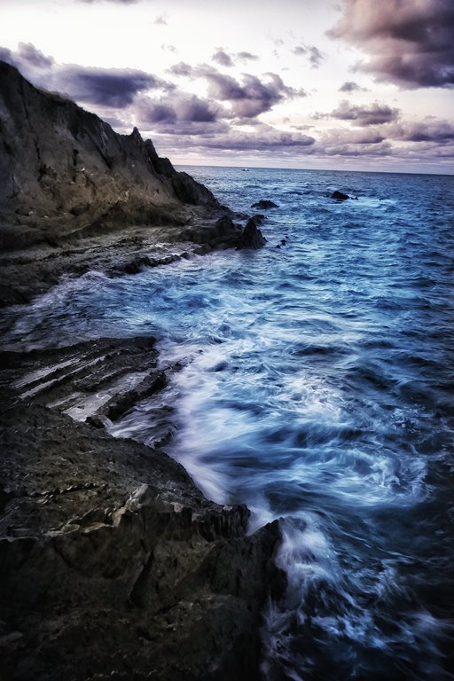 Fotografía de un acantilado con el mar enrarecido y cielo nuboso.