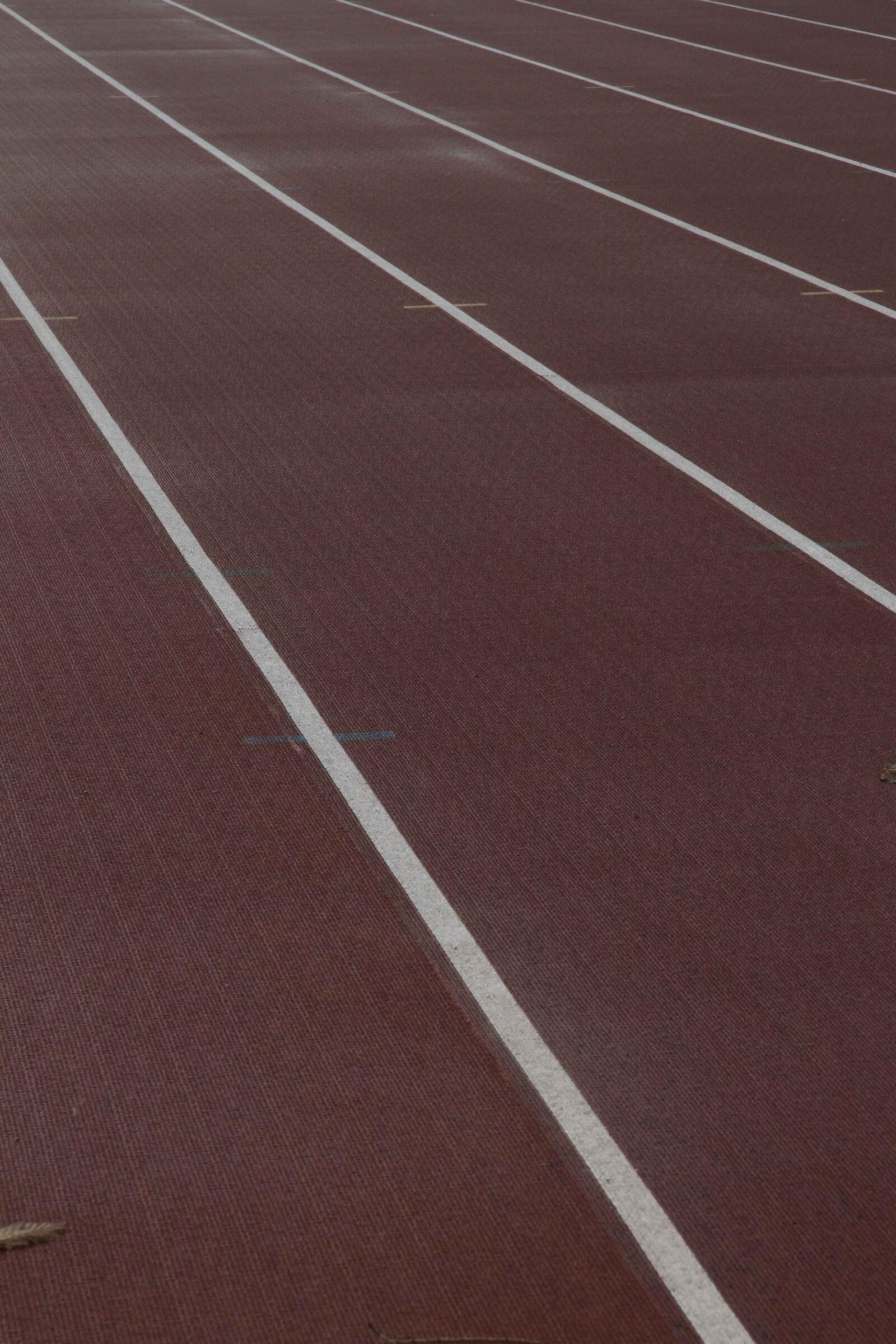 Líneas blancas en una pista de atletismo marrón-rojiza.