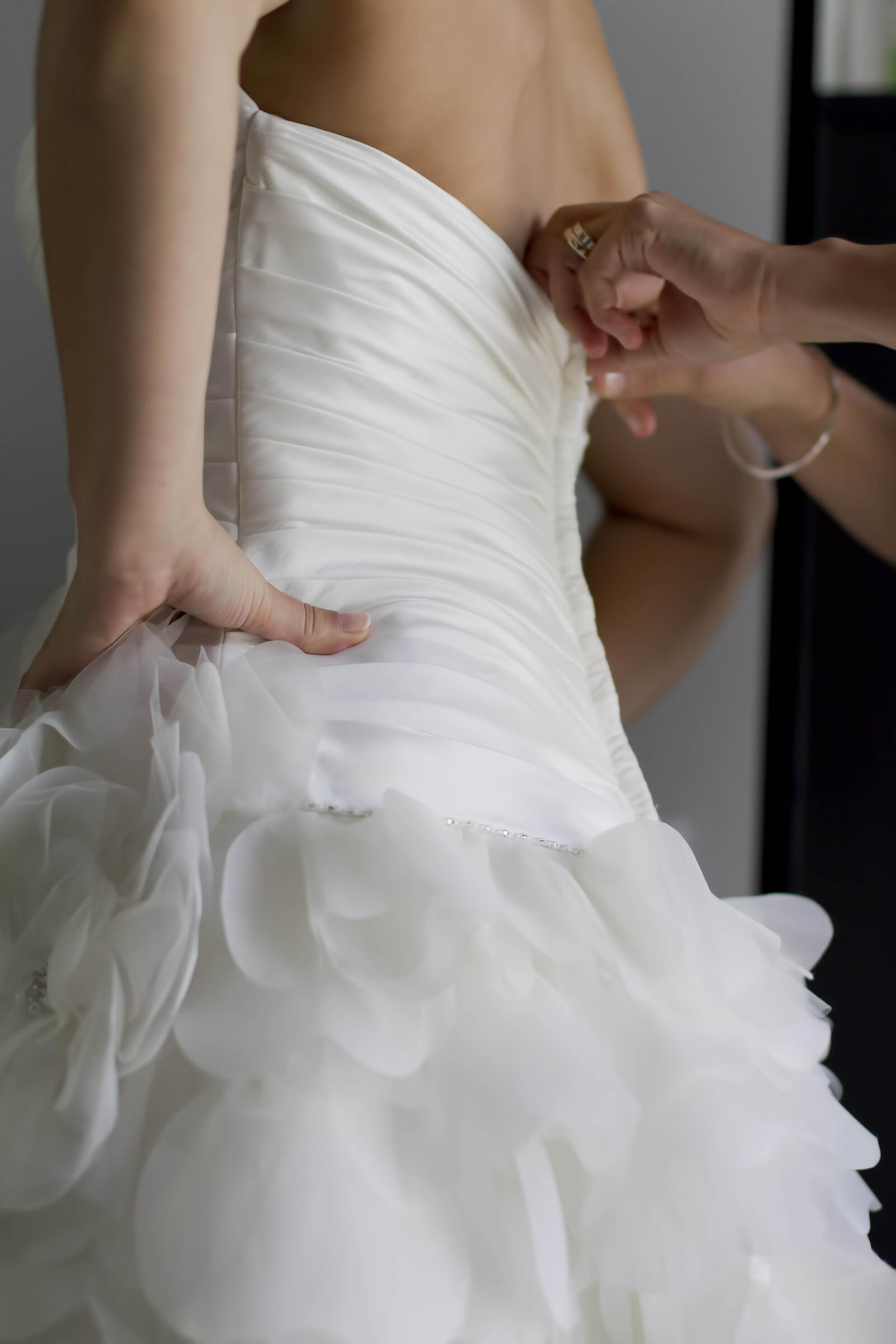 Novia siendo ajustada en su elegante vestido de boda blanco con detalles de volantes.