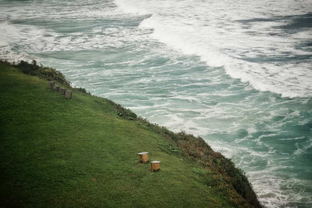 Fotografía de un prado verde junto a un acantilado que desciende hacia el mar.